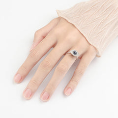 Evil Eye Rotatable Ring – Silver evil eye ring on model hand, blue stone, pink knit sleeve