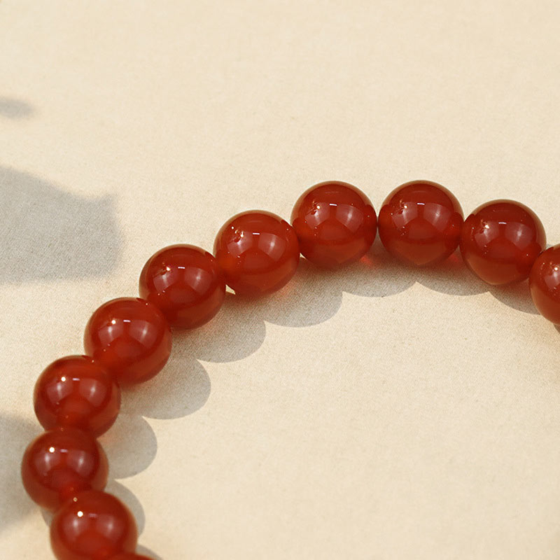 Red Agate Buddha Bracelet - Close-up of glossy 8mm red agate beads on light fabric