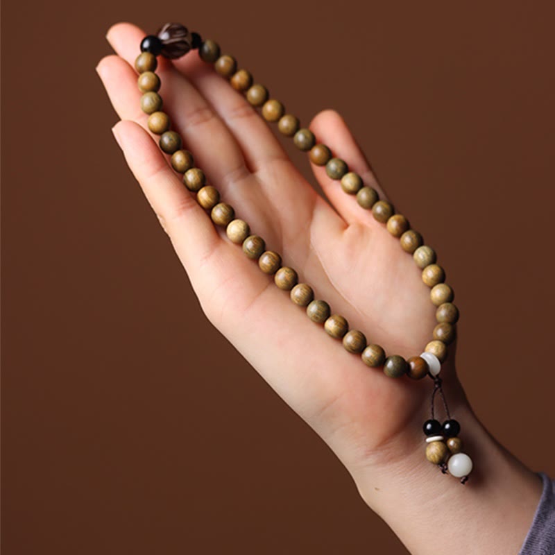 Green Sandalwood Lotus Bracelet – draped across open palm on brown backdrop, tassel detail