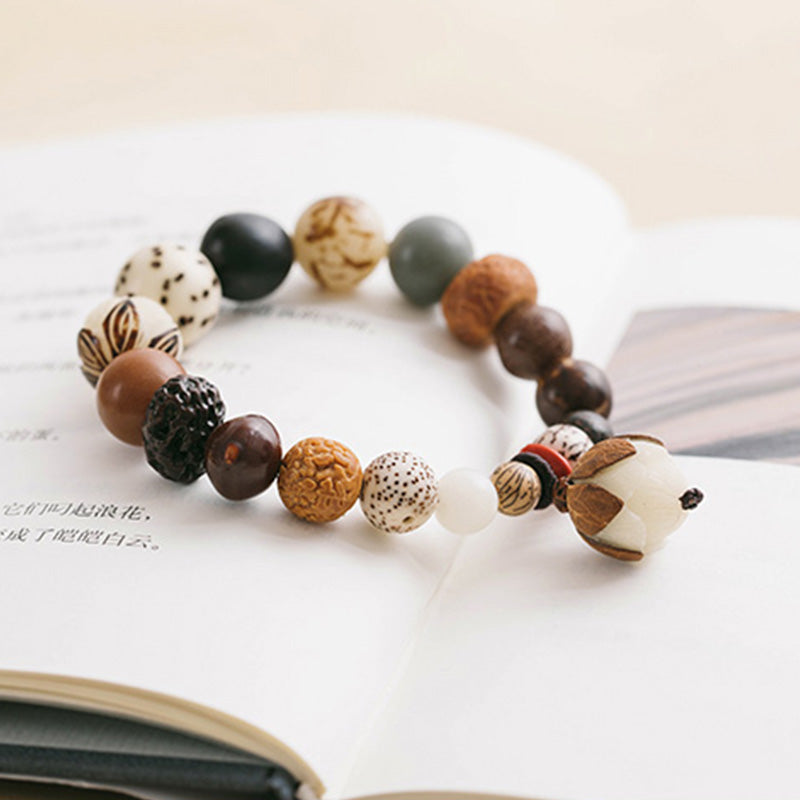 Bodhi Seed Lotus Mala – Angled flat lay on book with lotus carved focal bead, spiritual wrist mala