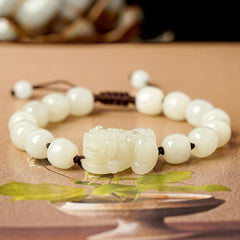 Hetian White Jade PiXiu Bracelet – White jade bracelet with black cord on decorative paper background
