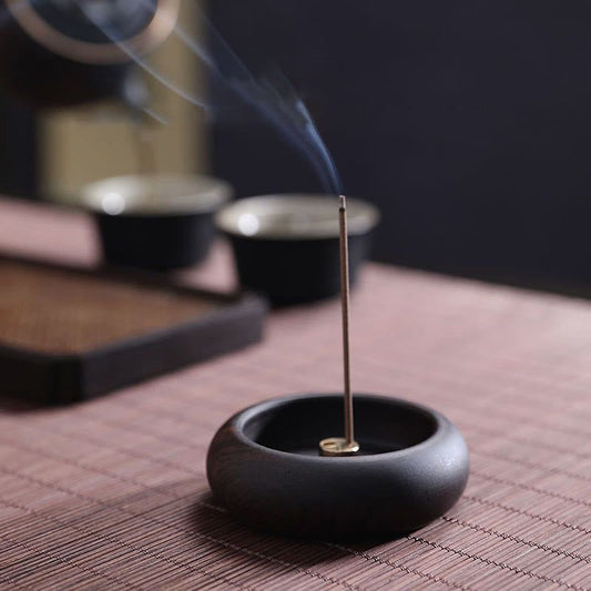 Stick incense burner with brass insert and smoke on woven mat, healing