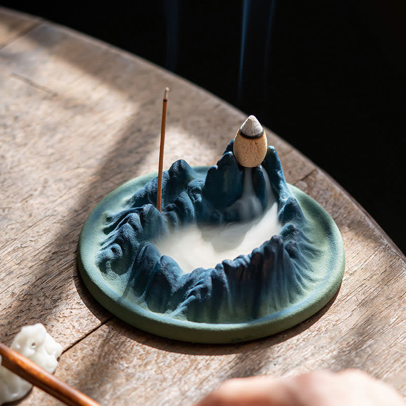 Ceramic Backflow Incense Burner – Blue-green mountain crater with dense smoke filling valley on rustic wood, zen