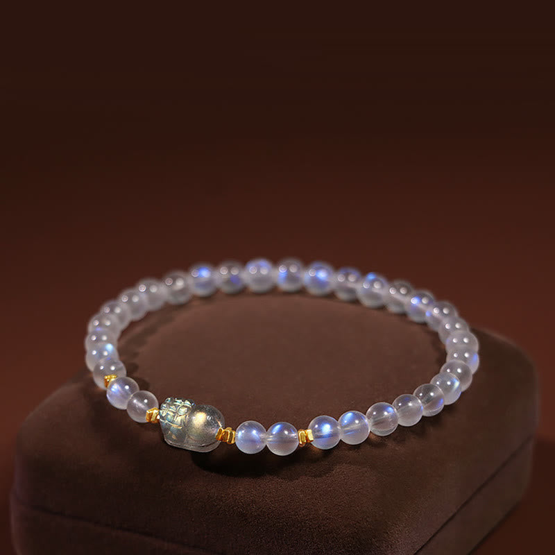 Moonstone PiXiu Bracelet – Luminous moonstone beads with gold PiXiu charm on velvet stand, healing bracelet