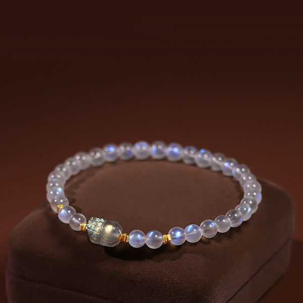 Moonstone PiXiu Bracelet – Luminous moonstone beads with gold PiXiu charm on velvet stand, healing bracelet