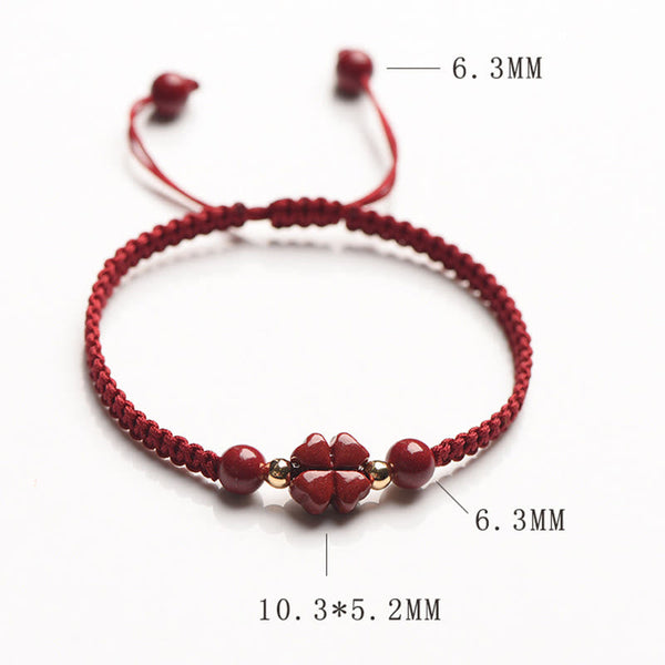 Adjustable red macrame bracelet with four-leaf clover charm and round cinnabar beads on white background, top-down product photography with dimension annotations