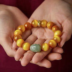 Zodiac Tiger Eye Jade Bracelet – Bracelet held in hands against maroon fabric