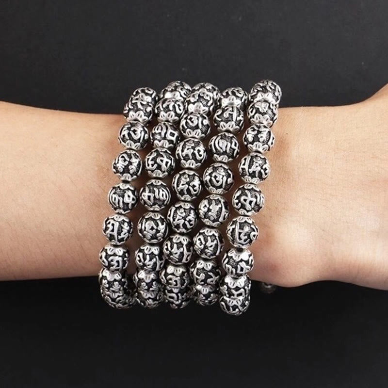 Om Mani Padme Hum Bracelet – Five stacked carved silver bracelets on wrist, black background