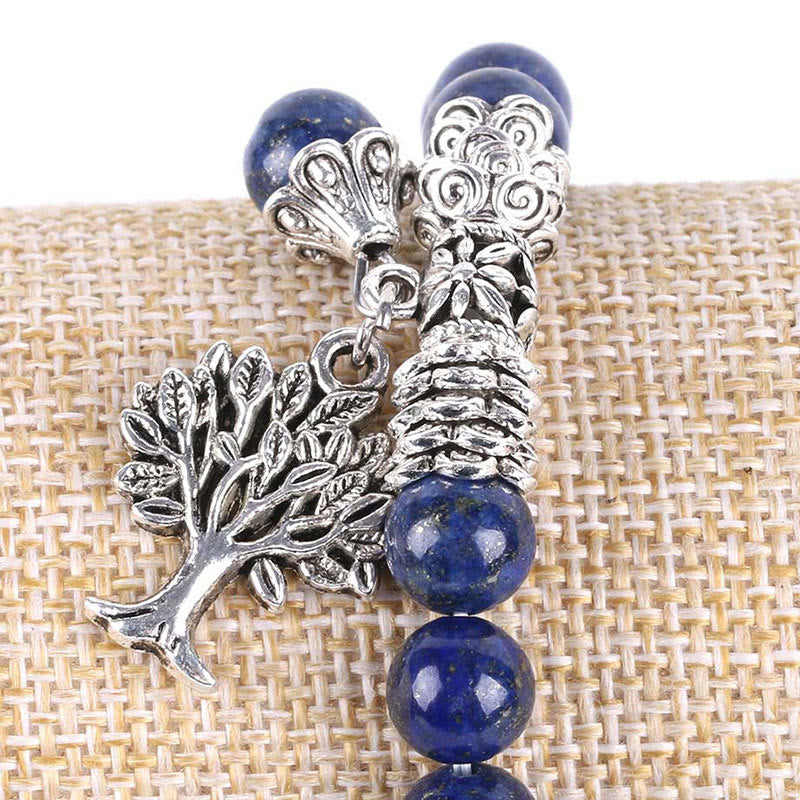 Tree of Life lapis lazuli bracelet with royal blue spherical beads and golden flecks, silver filigree caps, tree of life pendant on burlap.