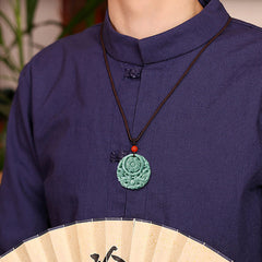 Dragon Jade Yin Yang Necklace – Green-white jade disc on dark cord with red accent on dark stone with wood elements, low side angle