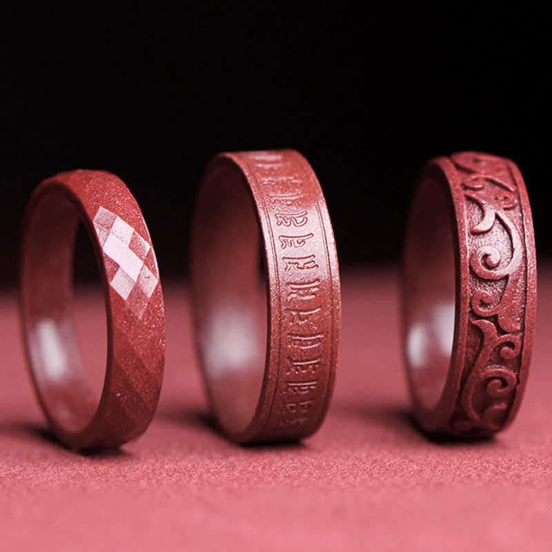 Cinnabar Om Mani Padme Hum Blessing Ring – three cinnabar ring variants, faceted inscribed and scrollwork designs, low-angle studio shot