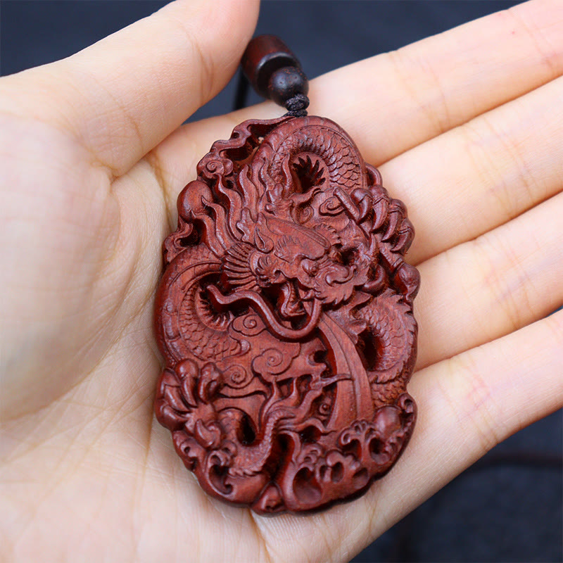 Lightning Jujube Wood Dragon Pendant - Held in palm against blue-gray bokeh, Meaningful