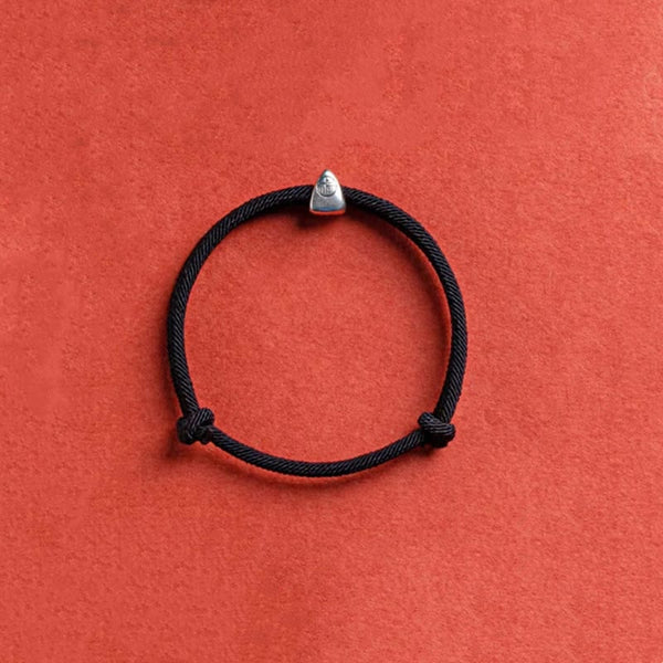 925 Silver Fu Character Braided Bracelet – Black cord bracelet with silver geometric charm and sliding knot on terracotta orange background, overhead flat lay