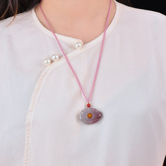 Jade Lotus Pendant – Purple carved lotus necklace worn on white blouse, amber center detail, elegant ethnic style