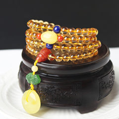 Citrine Mala Bracelet – Golden citrine bead strands on carved wooden stand, colorful accent beads