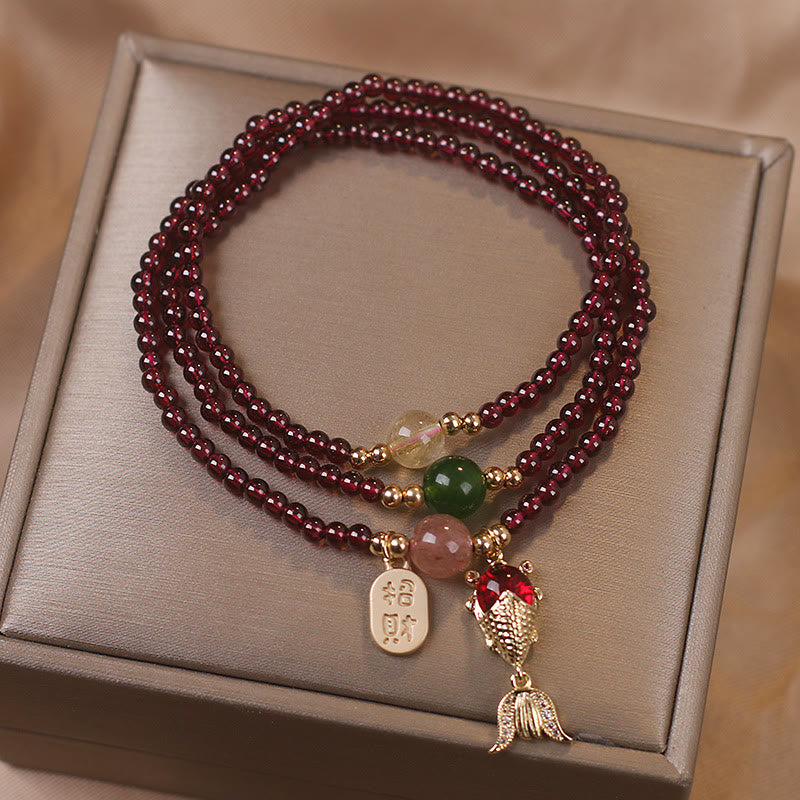Garnet koi fish triple-wrap bracelet with articulated gold fish pendant red crystal body and zhao cai wealth-attracting tag with jade strawberry quartz and citrine accent beads on gift box