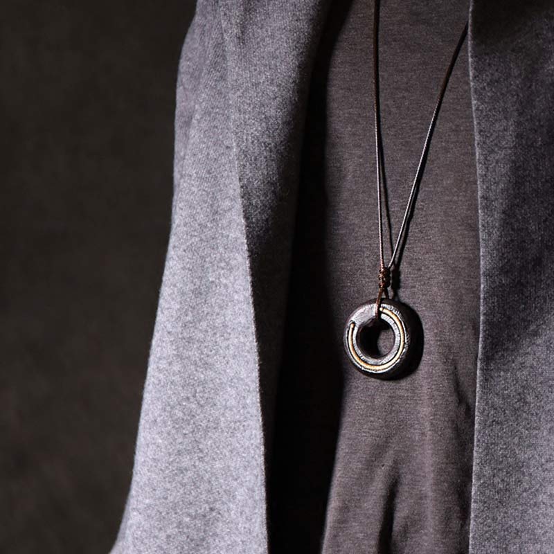 Dark Circle Pendant Necklace - geometric cutout ring on black cord, artisan men's jewelry on gray sweater