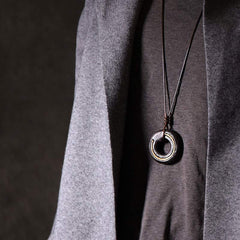 Dark Circle Pendant Necklace - geometric cutout ring on black cord, artisan men's jewelry on gray sweater