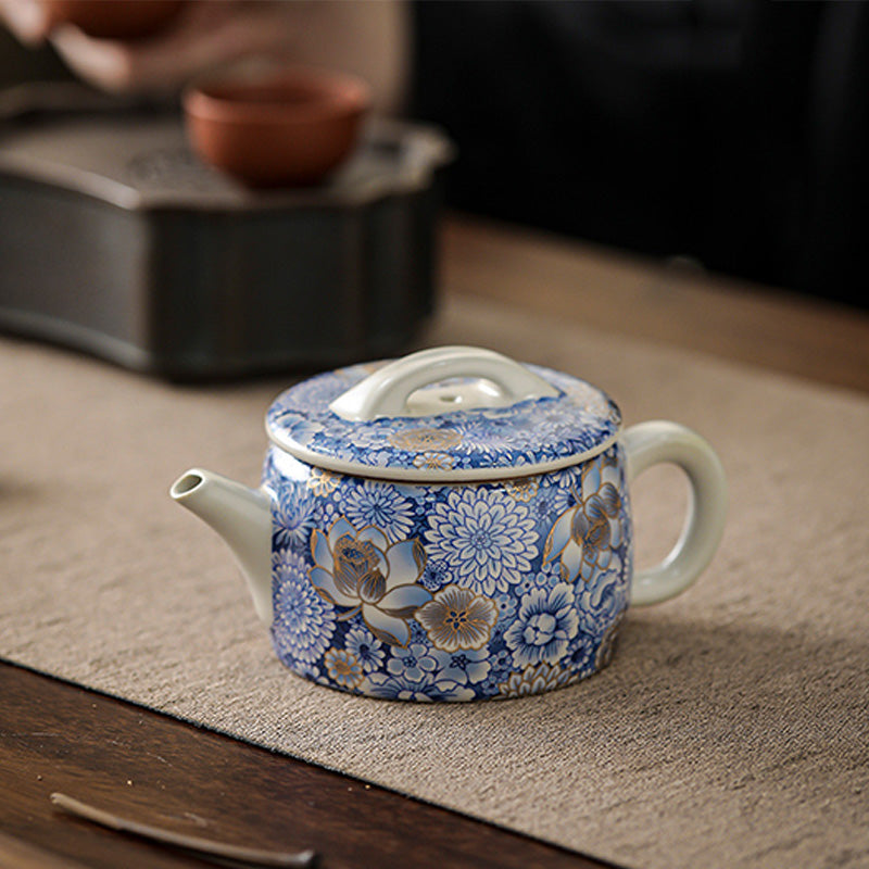 Lotus Chrysanthemum Ceramic Teapot - Blue-white teapot on woven mat with gold chrysanthemum, serene