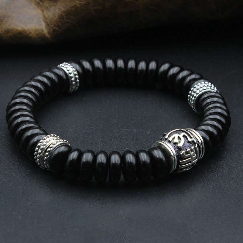 Om Mani Padme Hum Coconut Shell Bracelet – elevated angle on dark surface, silver accent bracelet