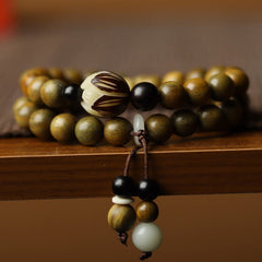 Green Sandalwood Lotus Bracelet – macro of carved lotus bead on wood, tassel with onyx drops
