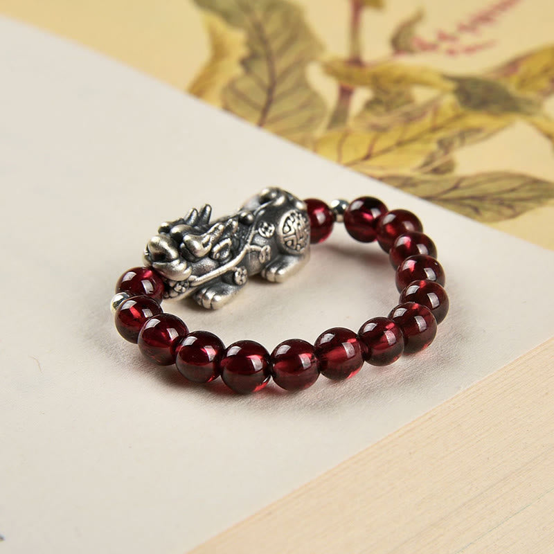 Silver Garnet PiXiu Ring – Garnet beads with detailed silver PiXiu on beige botanical background