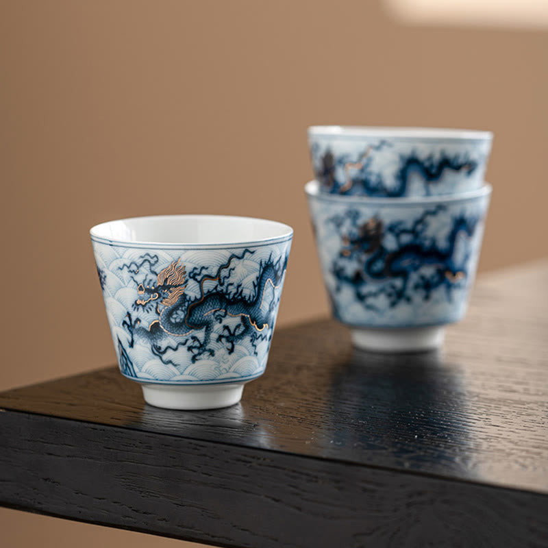Blue & White Dragon Ceramic Teacup – three cups stacked on dark wood, cloud and wave motifs, gongfu