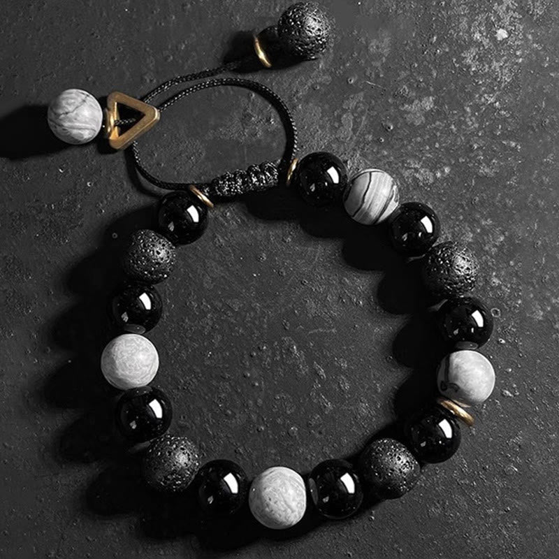 Black Obsidian Lava Rock Yin Yang Bracelet - overhead flat lay on dark stone surface, adjustable closure system, gold accents