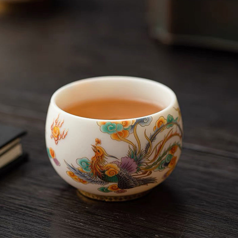 Dragon Phoenix Clouds Ceramic Teacup - Phoenix teacup with amber tea on wooden surface, elegant