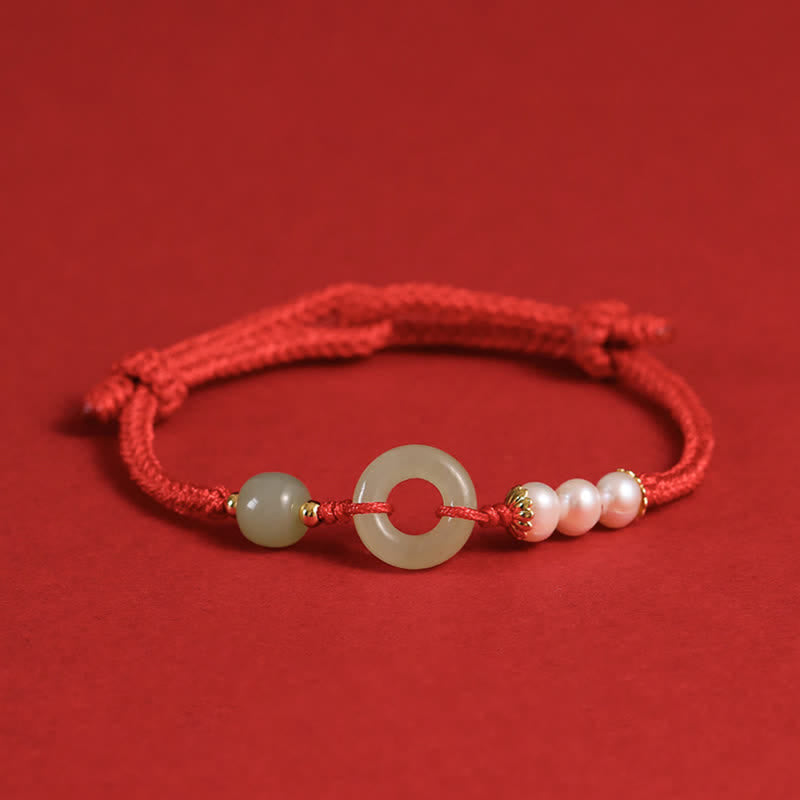 Hetian Jade Pearl Peace Buckle Bracelet – red braided cord with jade disc and pearls on red matte background, low three-quarter angle