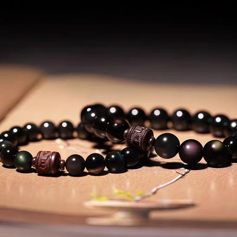 Gold Sheen & Rainbow Obsidian Fu Bracelet – two bracelets on open book, obsidian bead detail
