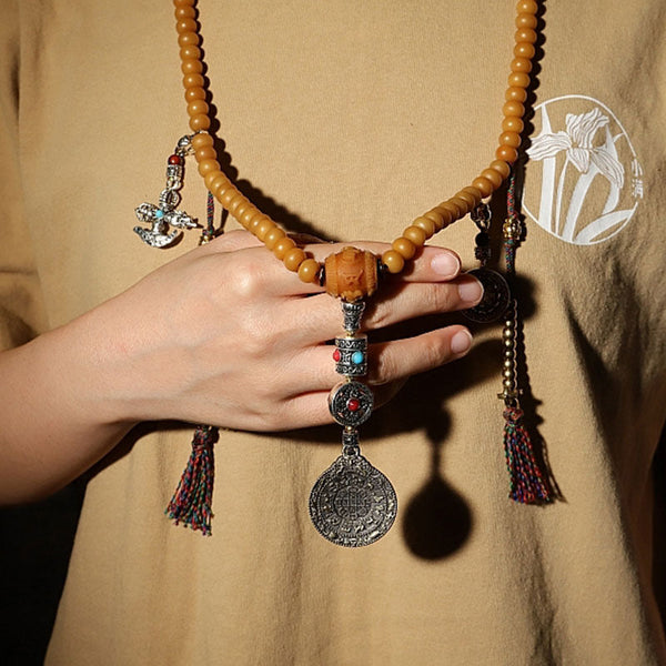108 Bodhi Seed Mala Bracelet – Hand holding amber mala necklace with silver pendant and stone inlays