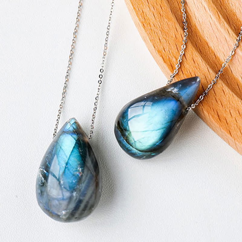 Labradorite water drop pendant necklace pair displaying two natural teardrop labradorite cabochons with vibrant blue-cyan iridescent flash on silver chains with light oak wood accent