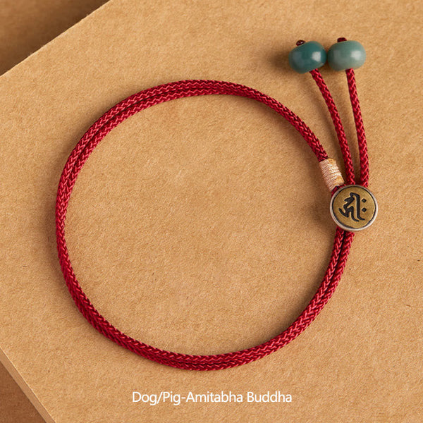 925 Silver Zodiac Natal Buddha Red String Bracelet flat lay, Dog and Pig Amitabha Buddha mantra charm, two-tone silver and gold circular medallion, teal green jade terminal beads, burgundy braided cord