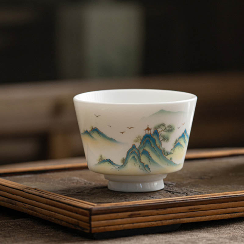 Ceramic Kung Fu Tea Cup – held in hand showing ribbed base, blue mountain panorama, translucent jade-like porcelain