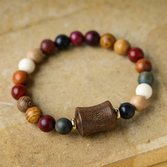 Multicolored Sandalwood Prayer Bracelet – Single strand flat lay on kraft surface, multi-wood beads