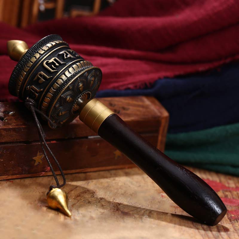 Copper Meditation Prayer Wheel – Dark bronze drum with gold accents on aged wood, meditation
