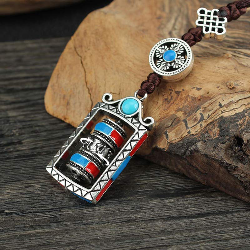 Om Mani Padme Hum Prayer Wheel Keychain – Three-quarter view on dark wood surface with bark prop, Buddhist keychain