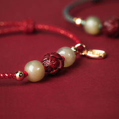 Hetian Jade Cinnabar Lotus Bracelet – Macro close-up of carved cinnabar lotus bead on red cord, bead detail
