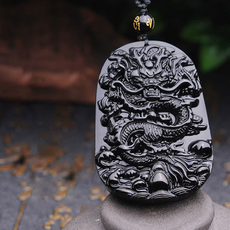 Black Obsidian Dragon Pendant – Angled dragon relief on gray stone pedestal, bold