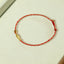14K Gold Plated Koi Braided Bracelet – worn on wrist showing gold koi pendant on red braided string, luck jewelry