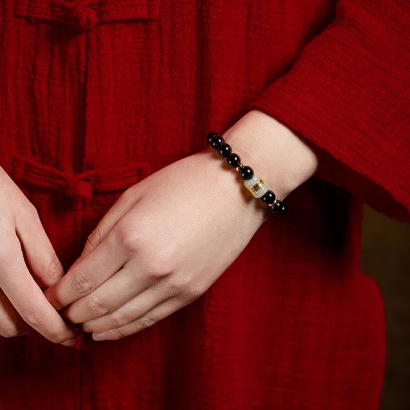 Black Obsidian Jade Bracelet – Close-up on wrist wearing bracelet with traditional Chinese red garment background
