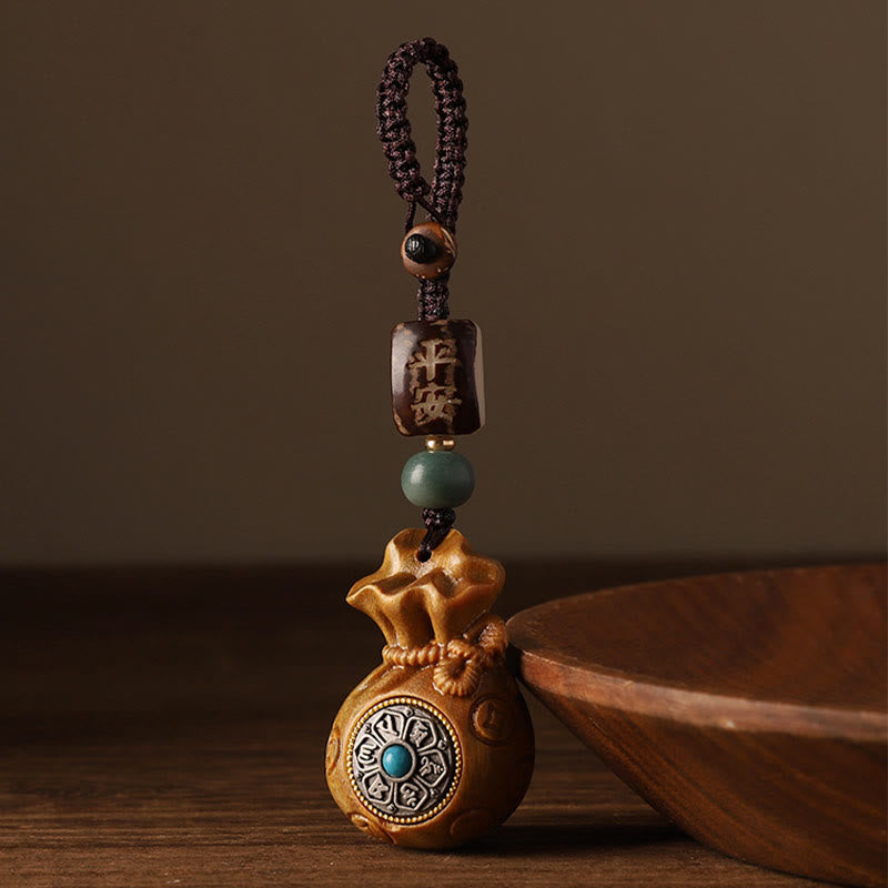 Sandalwood Money Bag Mantra Hanging - Dark bag with mantra medallion on wood surface
