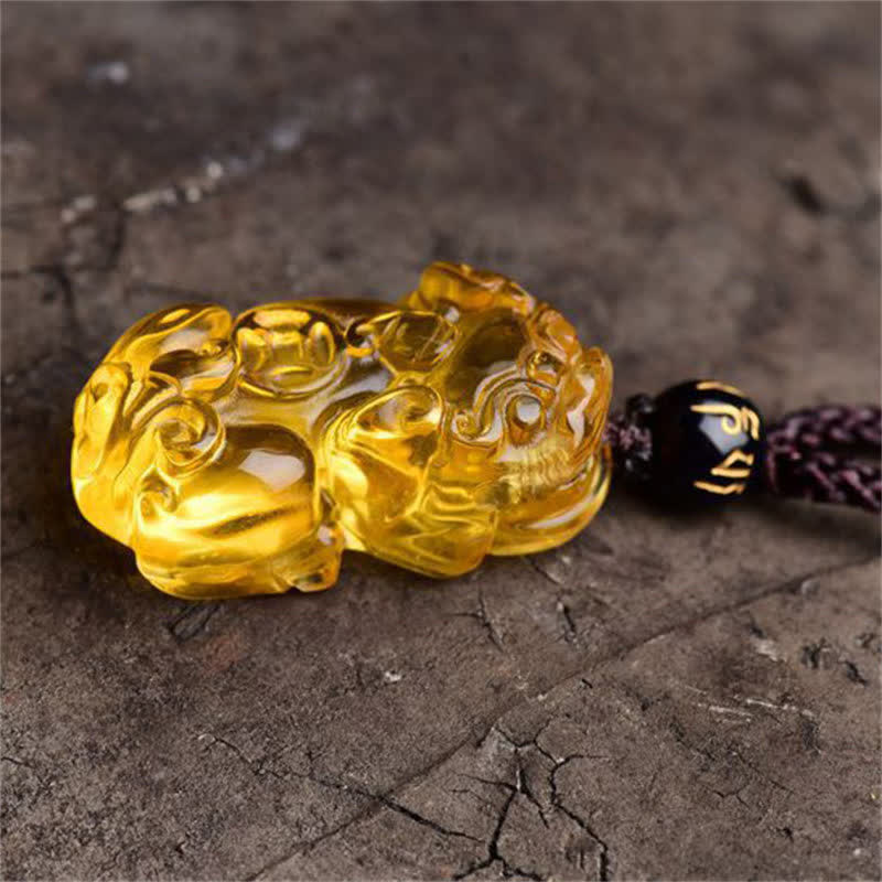 Citrine PiXiu Necklace Pendant – Close-up of carved citrine PiXiu on cracked stone, detailed craftsmanship