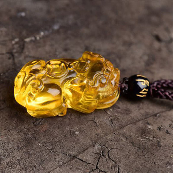 Citrine PiXiu Necklace Pendant – Close-up of carved citrine PiXiu on cracked stone, detailed craftsmanship