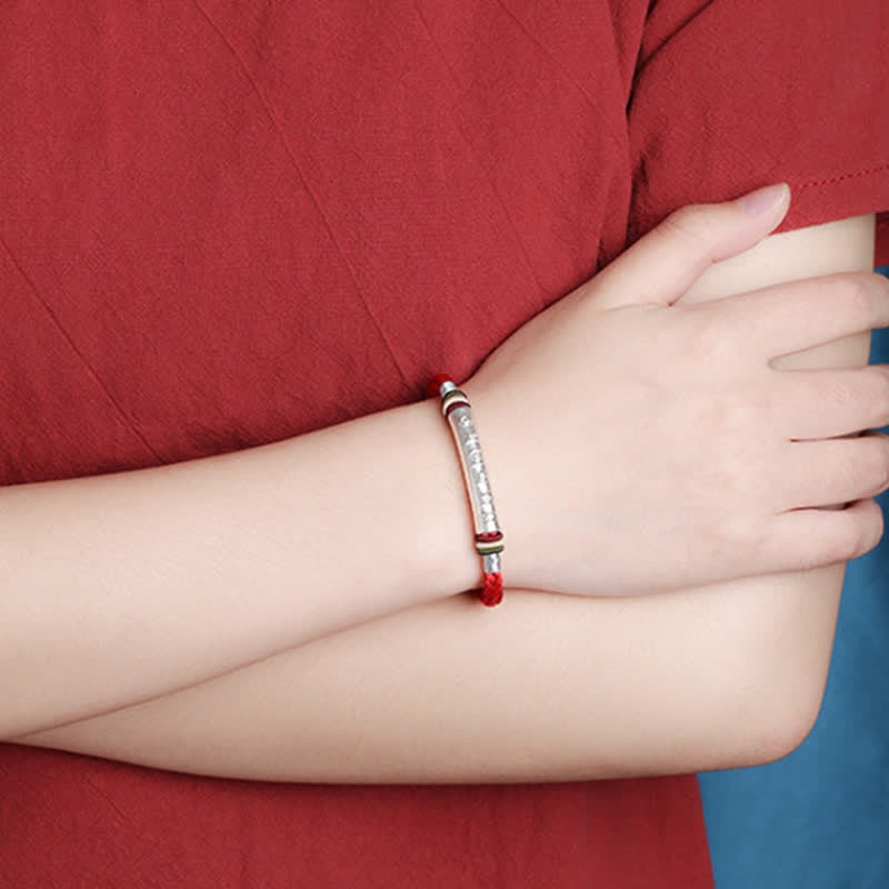Om Mani Padme Hum Red String Bracelet – Silver engraved cylinder on red cord, lifestyle wrist shot