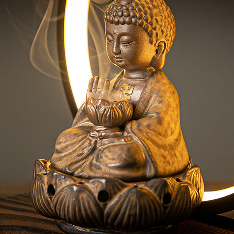 Buddha backflow burner with LED halo ring and active smoke, bronze finish on dark wood, swastika symbol