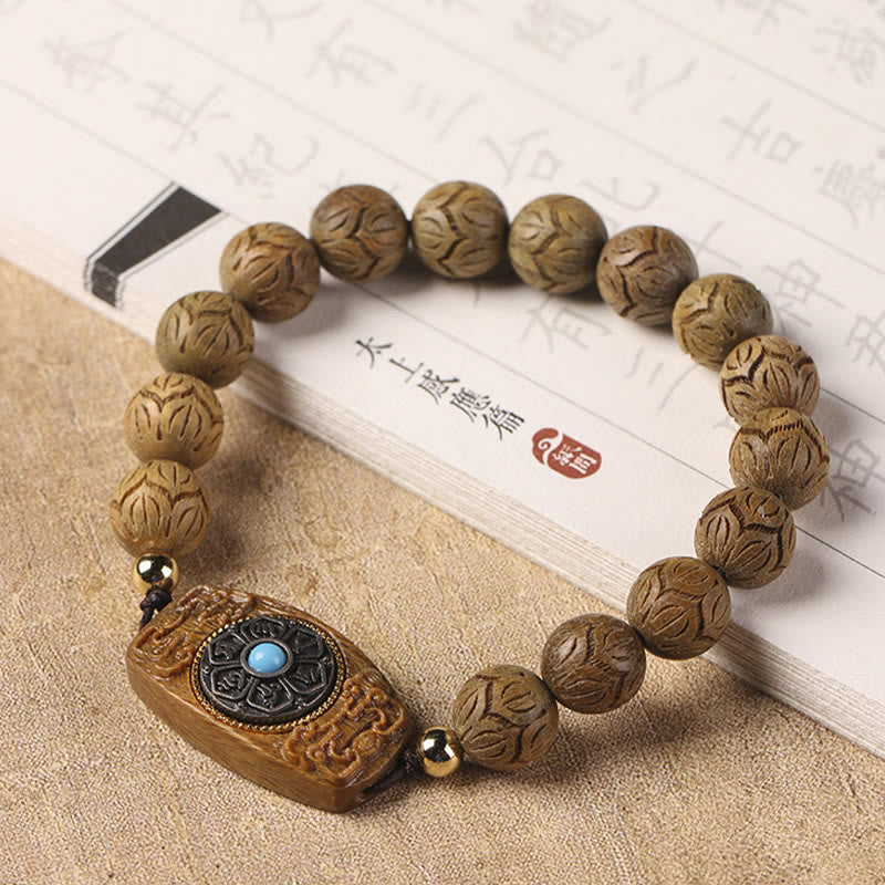 Green Sandalwood & Ebony Soothing Bracelet – angled view beside traditional scripture book, hand-carved lotus beads and tu...