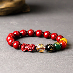 Cinnabar PiXiu Blessing Bracelet – Red cinnabar beads with multicolor charms on gray with driftwood