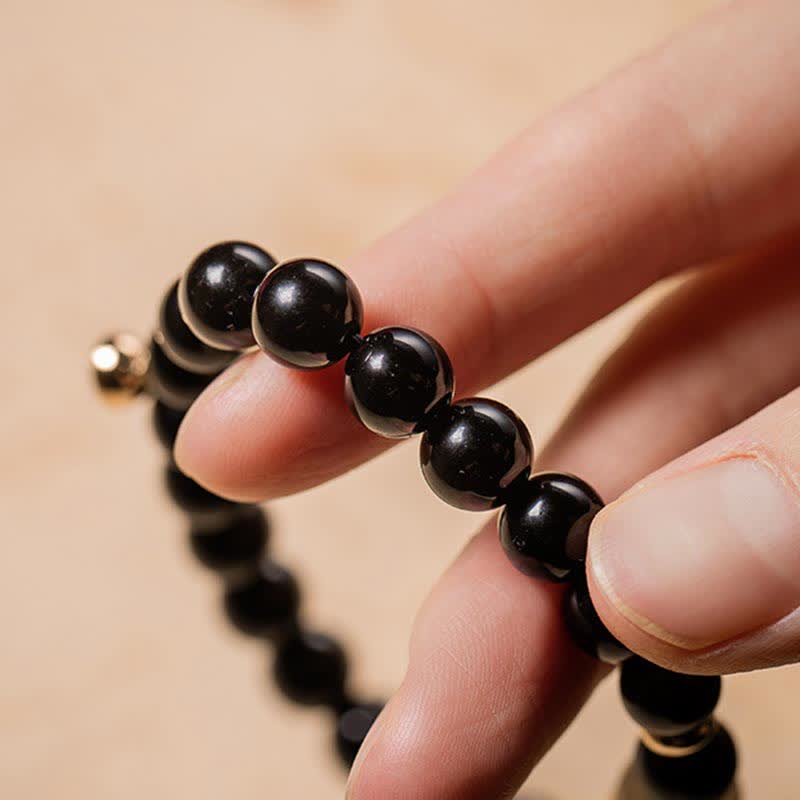 Black Obsidian Jade Bracelet – Macro detail of glossy black obsidian beads with gold spacer, natural stone texture